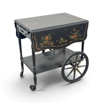 Sale Photo Thumbnail #156: Vintage black lacquered drop-leaf tea cart featuring hand-painted floral and bird motifs, a lower shelf, and large spoked wheels.