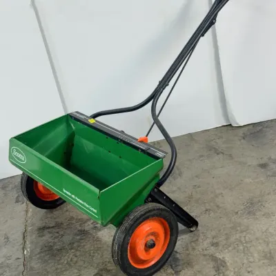 Sale Photo Thumbnail #226: Scotts drop spreader with precision flow control, featuring a green hopper, orange wheels, and a black handle.