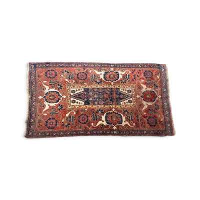 Sale Photo Thumbnail #302: Antique Persian area rug featuring a central geometric medallion surrounded by intricate floral motifs in shades of red, navy blue, and cream.