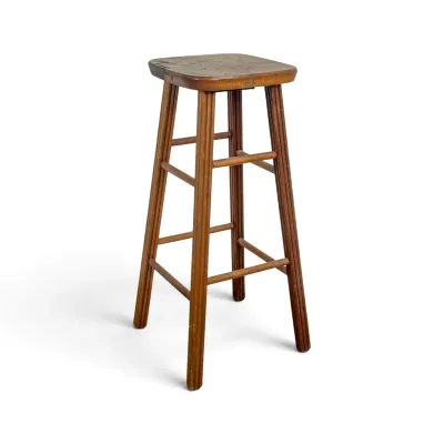 Sale Photo Thumbnail #77: Vintage wooden bar stool featuring fluted legs, a square seat with rounded corners, and double-tier stretchers showing a naturally weathered patina.