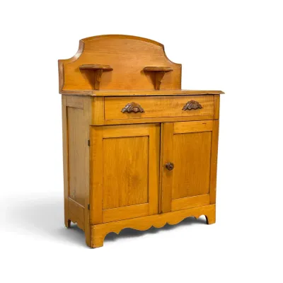 Sale Photo Thumbnail #265: Antique pine washstand featuring a shaped backsplash with two small candle shelves, a single drawer with carved wooden pulls, and a lower two-door cabinet.