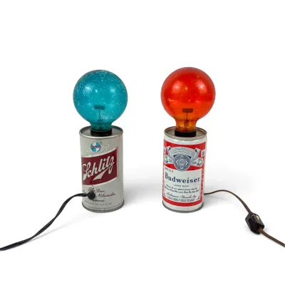 Sale Photo Thumbnail #26: Pair of vintage novelty beer can lamps, featuring a Schlitz can with a blue bulb and a Budweiser can with a red bulb, circa 1970s.