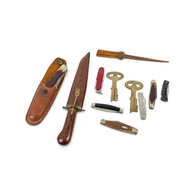 Sale Photo Thumbnail #25: Assortment of vintage pocket knives, a fixed-blade knife with a carved wooden handle and sheath, a folding knife in a leather holster, two brass keys, and a wooden awl.