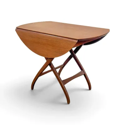 Sale Photo Thumbnail #8: Mid-century modern teak drop-leaf table with curved X-frame legs, showing some light surface wear.