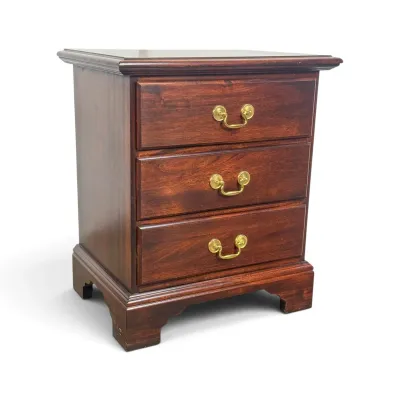 Sale Photo Thumbnail #83: Traditional cherry wood three-drawer nightstand with brass bail pulls and bracket feet.