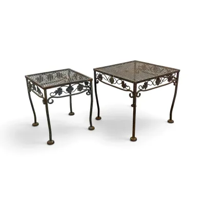 Sale Photo Thumbnail #216: Pair of vintage wrought iron nesting side tables featuring mesh tops, scrolled floral aprons, and a weathered, rusted patina.