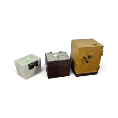 Sale Photo Thumbnail #131: Three vintage home safes, including a small grey Sentry key-lock box, a dark brown metal lockbox, and a larger gold-toned combination dial safe.