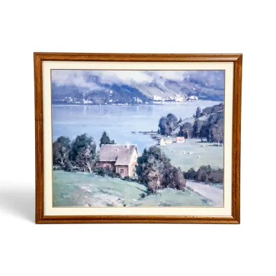 Sale Photo Thumbnail #138: Framed landscape print depicting a scenic lakeside village with cottages, mountains, and water, housed in a wooden frame with a white mat.