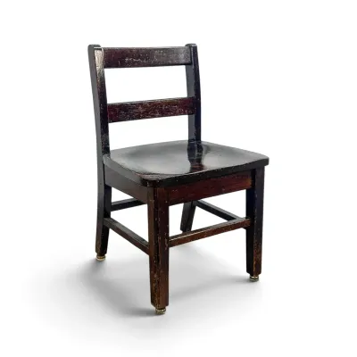 Sale Photo Thumbnail #280: Vintage child's wooden schoolhouse chair with a dark finish, ladder-back design, and metal glides on the legs.