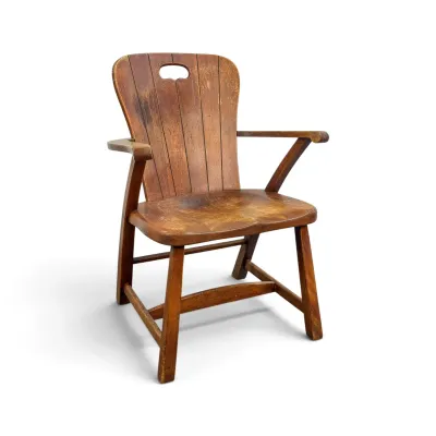 Sale Photo Thumbnail #50: Vintage wooden armchair featuring a slatted back with a cutout handle, contoured seat, and a warm, distressed finish.