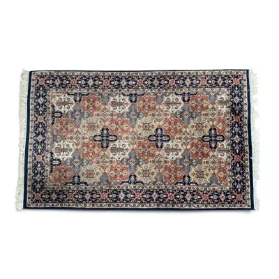 Sale Photo Thumbnail #291: Persian-style area rug featuring an intricate geometric and floral pattern in shades of navy blue, rust, and cream, finished with white fringe on the ends.