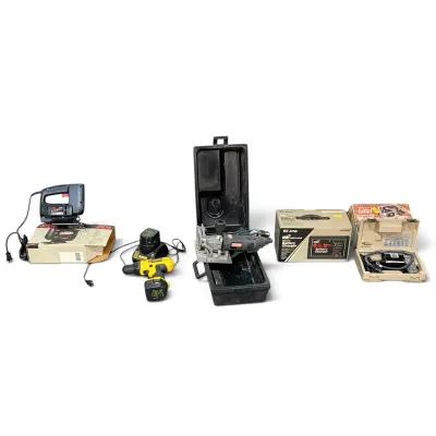 Sale Photo Thumbnail #250: Assortment of power tools and equipment, including a Skil jigsaw with box, a DeWalt cordless drill with charger, a biscuit joiner in a hard case, a battery charger in its box, and a portable air compressor in a case.