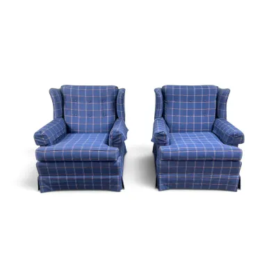 Sale Photo Thumbnail #111: Pair of vintage wingback armchairs upholstered in a blue and red plaid fabric, featuring button-tufted backs and pleated skirts.