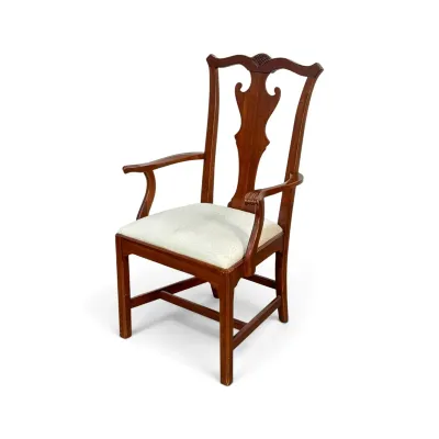 Sale Photo Thumbnail #316: Queen Anne style mahogany armchair featuring a carved splat back, curved armrests, and a light-colored upholstered seat cushion.