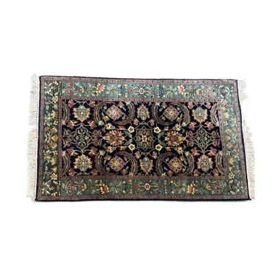 Sale Photo Thumbnail #285: Small Persian-style area rug featuring a dark navy field with intricate floral motifs, framed by a sage green border and finished with white fringe.