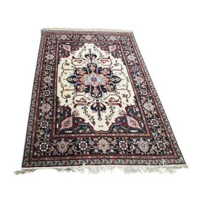 Sale Photo Thumbnail #304: Traditional Persian-style area rug featuring a central medallion on an ivory field, surrounded by navy, burgundy, and light blue floral motifs and a detailed border with fringed ends.