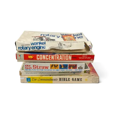 Sale Photo Thumbnail #22: Stack of vintage board games and model kits, including a Wankel Rotary Engine model kit, Milton Bradley Concentration game, Schaper The Last Straw game, and Cadaco Ten Commandments Bible Game, showing moderate box wear.