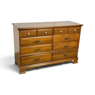 Sale Photo Thumbnail #102: Vintage Ethan Allen maple double dresser, featuring ten drawers with a mix of white ceramic knobs and brass batwing pulls, resting on bracket feet.