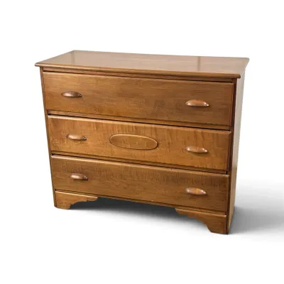 Sale Photo Thumbnail #118: Vintage three-drawer wooden dresser featuring carved wooden pulls, a decorative oval motif on the middle drawer, and a scalloped base.
