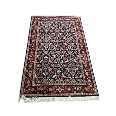 Sale Photo Thumbnail #308: Traditional Persian-style area rug featuring an intricate floral and vine pattern in navy blue, red, and cream tones, finished with a white fringed border.