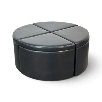 Sale Photo Thumbnail #309: Modern black faux leather modular ottoman set, consisting of four wedge-shaped pieces that form a circular coffee table or seating arrangement.