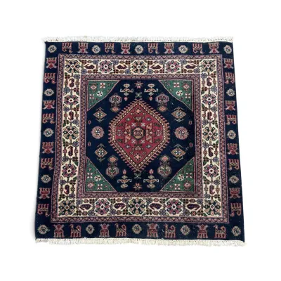 Sale Photo Thumbnail #289: Small Persian-style hand-knotted wool rug featuring a central red diamond medallion on a navy blue field with green corner accents and a fringed border.