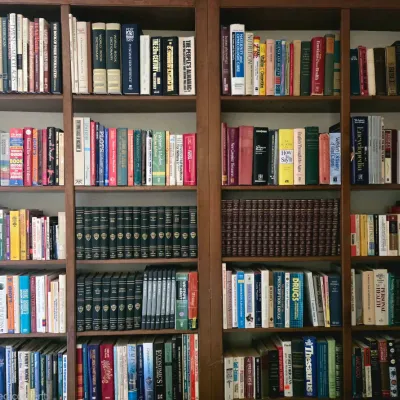 Large wooden bookcase unit filled with a diverse collection of vintage and modern reference books, encyclopedias, and non-fiction titles.