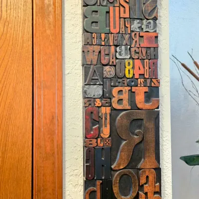 Sale Photo Thumbnail #55: Vintage wooden letterpress block wall art, featuring a collage of various-sized letters and numbers in natural wood, black, and red tones.