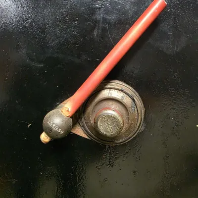 Detail view of an antique Mosler Safe Co. combination dial and red-wrapped handle assembly set on a textured black metal door, displaying...