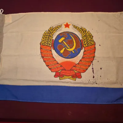 Sale Photo Thumbnail #28: Vintage Soviet Union state flag featuring the USSR coat of arms on a white and blue field, showing some minor staining and wear.