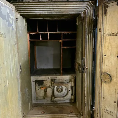Antique Mosler heavy iron floor safe featuring double outer doors, wooden cubby organizers, and an inner steel compartment.