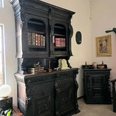 Large, heavily carved dark oak Renaissance Revival hutch with intricate relief panels, accompanied by a matching side cabinet.