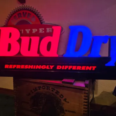 Sale Photo Thumbnail #18: Vintage Bud Dry illuminated bar sign featuring red and blue lettering with the slogan "Refreshingly Different" on a black base, circa 1990s.