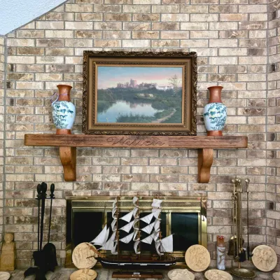 Fireplace mantel display featuring an framed landscape painting flanked by ceramic vases, sitting above a wooden model sailing ship,...