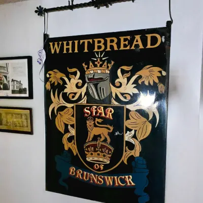 Vintage Whitbread 'Star of Brunswick' pub sign painted with heraldic crest and knight's helmet, mounted on a wrought iron...