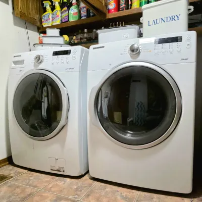 Matching white Samsung front-loading washer and dryer set, featuring steam cycles and VRT technology.
