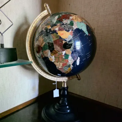 World globe mounted on a brass meridian and black metal pedestal base.