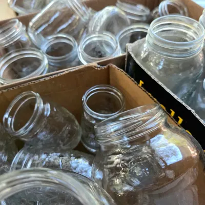 Large collection of clear glass canning jars in various sizes, organized in cardboard boxes.