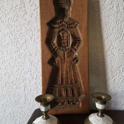 Sale Photo Thumbnail #44: Vintage hand-carved wooden speculaas cookie mold depicting a traditional figure, shown alongside a pair of brass and mother-of-pearl candlesticks.
