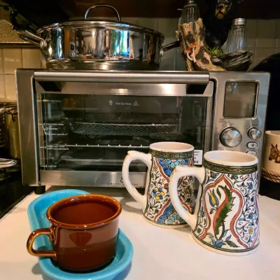 Countertop assortment featuring an Emeril Lagasse stainless steel toaster oven air fryer, stainless steel pot, two hand-painted ceramic...