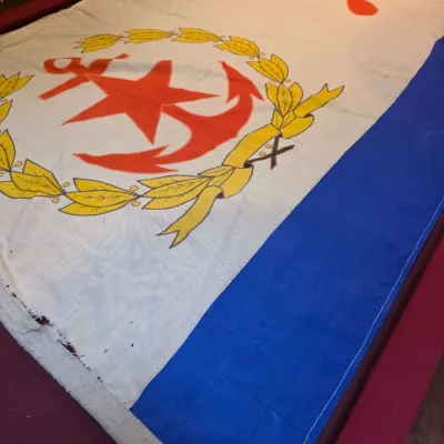 Sale Photo Thumbnail #30: Vintage Soviet Navy ensign flag, featuring the red star, hammer and sickle, and anchor emblem, showing some wear and fraying along the edges.