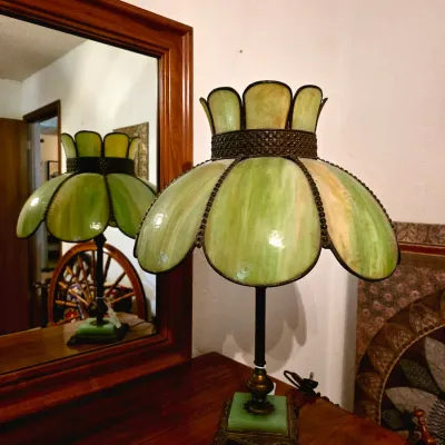 Vintage slag glass table lamp featuring a green tulip-style shade, metal base, and green marble accent, shown on a wooden dresser in...