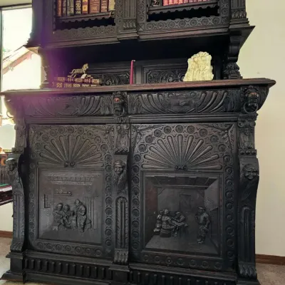 Heavily carved antique Renaissance Revival style dark wood hutch featuring relief-carved tavern scenes on the lower cabinet doors and...