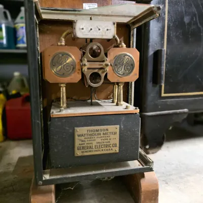 Antique General Electric Thomson Watthour Meter, early 20th century, housed in a wood and glass display cabinet with visible brass...