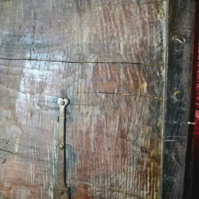Sale Photo Thumbnail #4: Detail of an antique wooden chest lid showing aged wood grain, iron strap hinges, and hand-forged hardware.