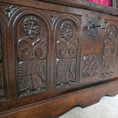 Sale Photo Thumbnail #5: Antique carved oak coffer featuring detailed relief carvings of figures in arched panels and a metal key in the lock.