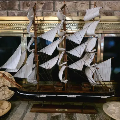 Sale Photo Thumbnail #52: Vintage wooden model of the Cutty Sark clipper ship, featuring detailed rigging and white sails, displayed on a wooden stand.