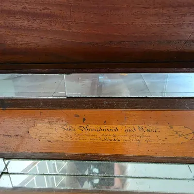 Maker's mark on an antique John Broadwood and Son piano, dated 1800, featuring inlaid wood detail and mirrored accents.