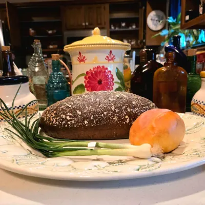 Decorative ceramic platter holding faux food items, displayed alongside colorful vintage glassware and hand-painted ceramic canisters.