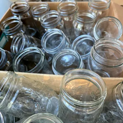 Large collection of clear glass canning jars in various sizes, organized in cardboard boxes.